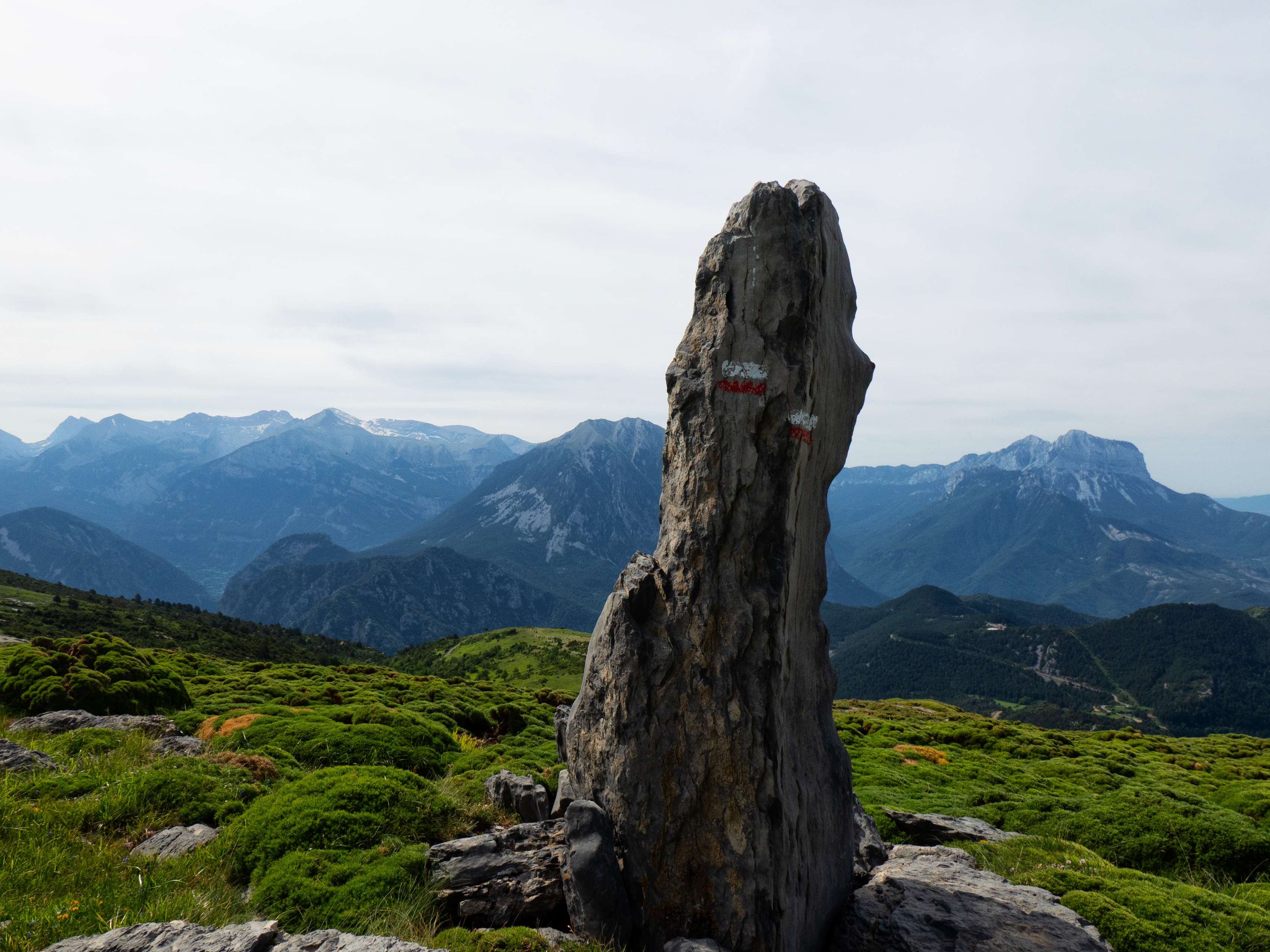 Sobre los 1.800 metros, el sendero se une definitivamente a la pista en el mismo punto donde encontramos este monolito, que podría pasar perfectamente por un menhir colocado por nuestros antepasados de no ser porque parece tratarse de una roca colocada por el maquinista que, en el siglo pasado, construyó la pista que estamos siguiendo. De hecho, si nos fijamos, veremos más de estos grandes monolitos, siempre cerca de la pista.