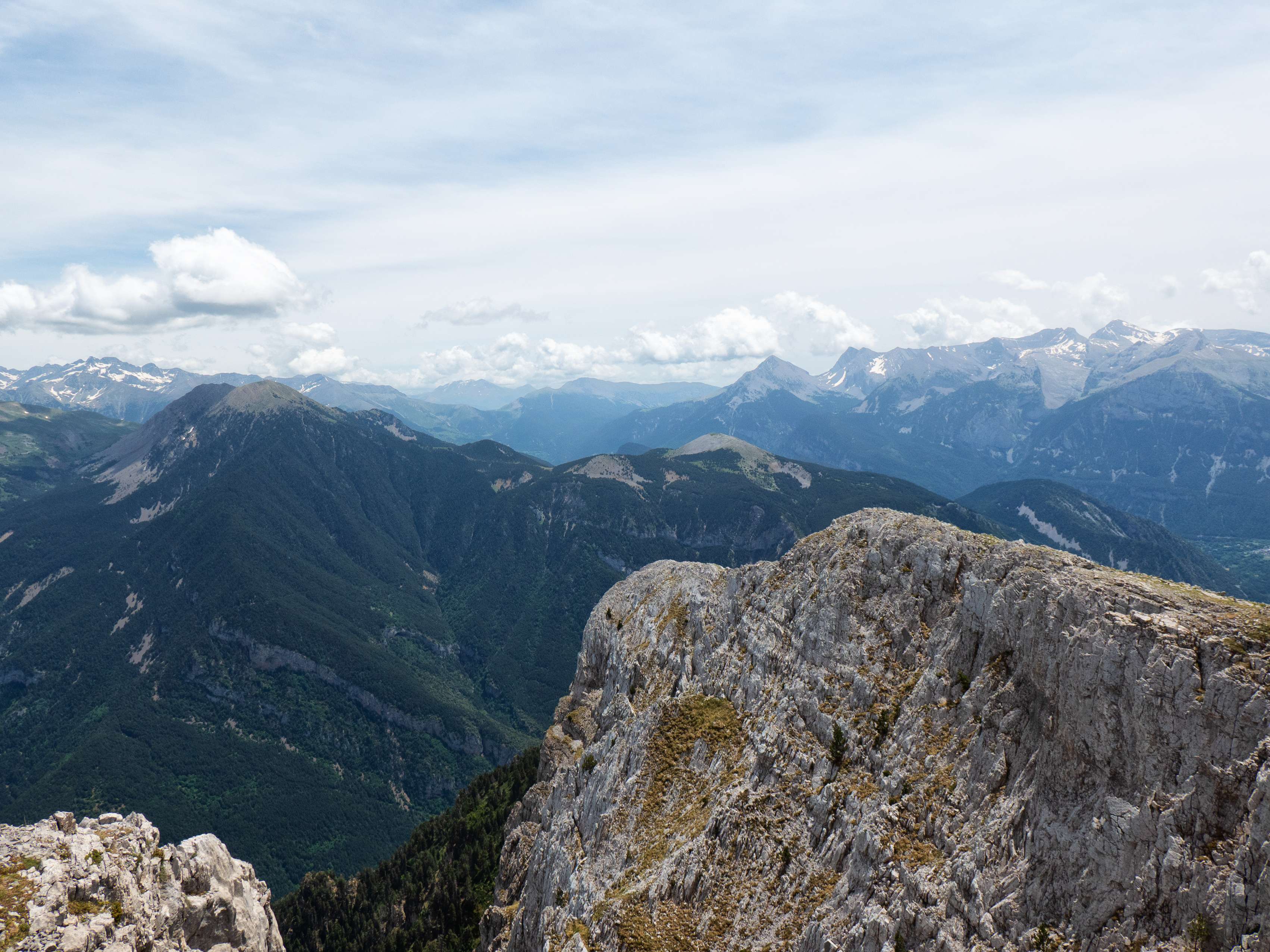 La sierra no termina abruptamente, sino que la arista sigue hacia el este hasta hundirse en el valle del Cinca, que discurre paralelo al del Cinqueta. En el horizonte, el extenso macizo de <a href="https://triptomontes.com/cotiella-y-cotielleta-por-el-circo-de-armena/">Cotiella</a> y la <a href="https://triptomontes.com/puntal-de-chia-y-casania-desde-el-refugio-de-marradetas/">sierra de Chía</a> cierran el panorama hacia levante.