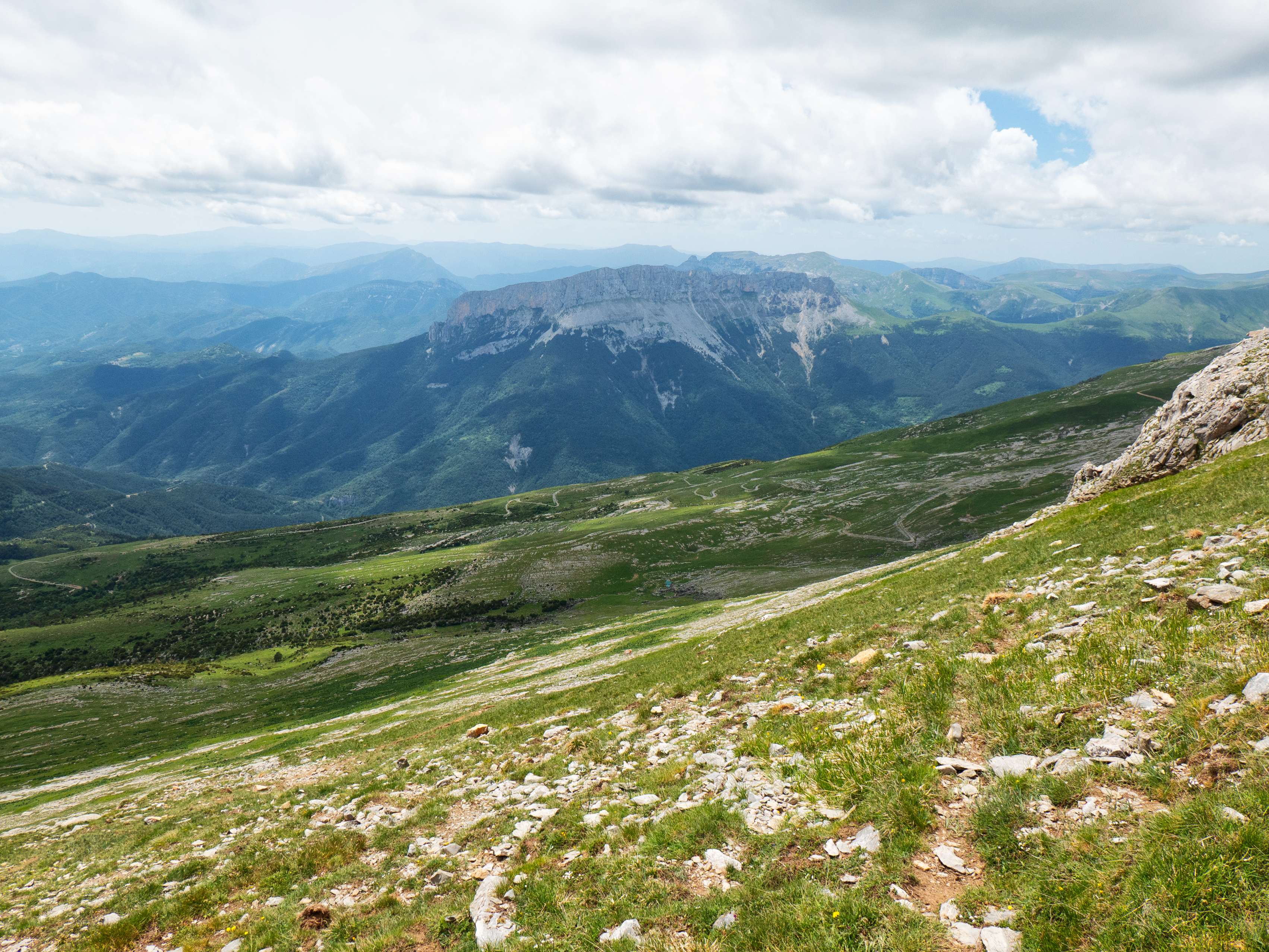 No hace falta llegar de nuevo a la cima sino que, cuando llegamos a la depresión previa a la arista afilada, saltamos a la cara sur de la montaña. El objetivo es claro: debemos llegar nuevamente a la pista, trazando una larga diagonal descendente por las campas calizas.