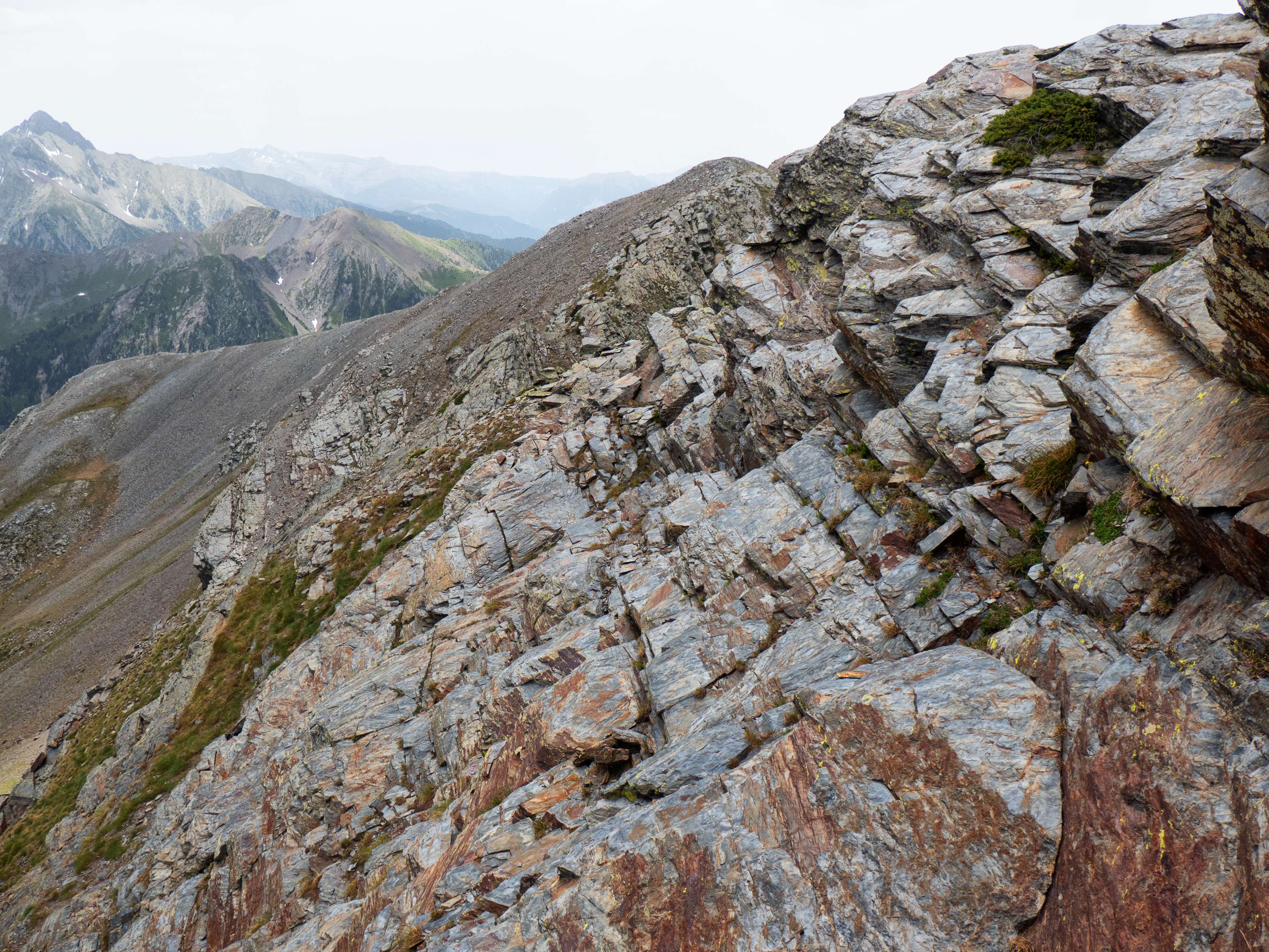 Esta vira se torna rocosa a medio recorrido, pero sigue sin ser demasiado complicada. Aún así, entre rocas encontramos algún corte con cierta altura que debemos destrepar, con algún paso de I grado superior. Poco a poco vamos bajando hasta una nueva brecha previa al segundo tramo de arista, que se ve más sencillo.