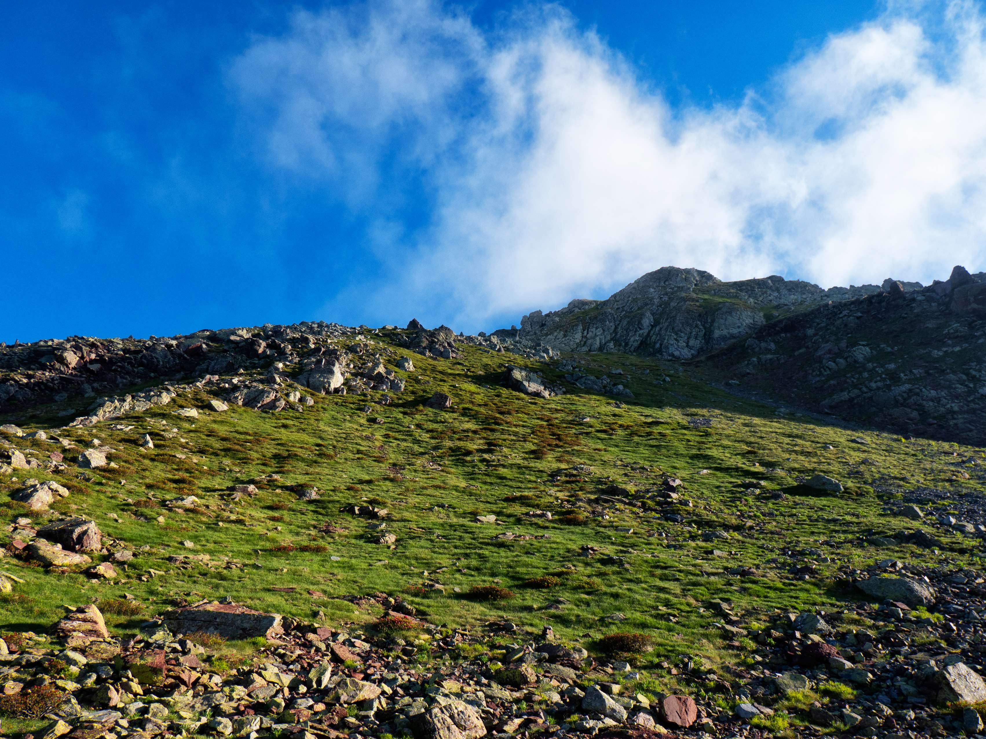 Después de saltar por los rojizos bloques, nos disponemos a afrontar la ladera. Efectivamente, la subida es muy vertical, pero, si vamos con cuidado, se hace bastante bien.