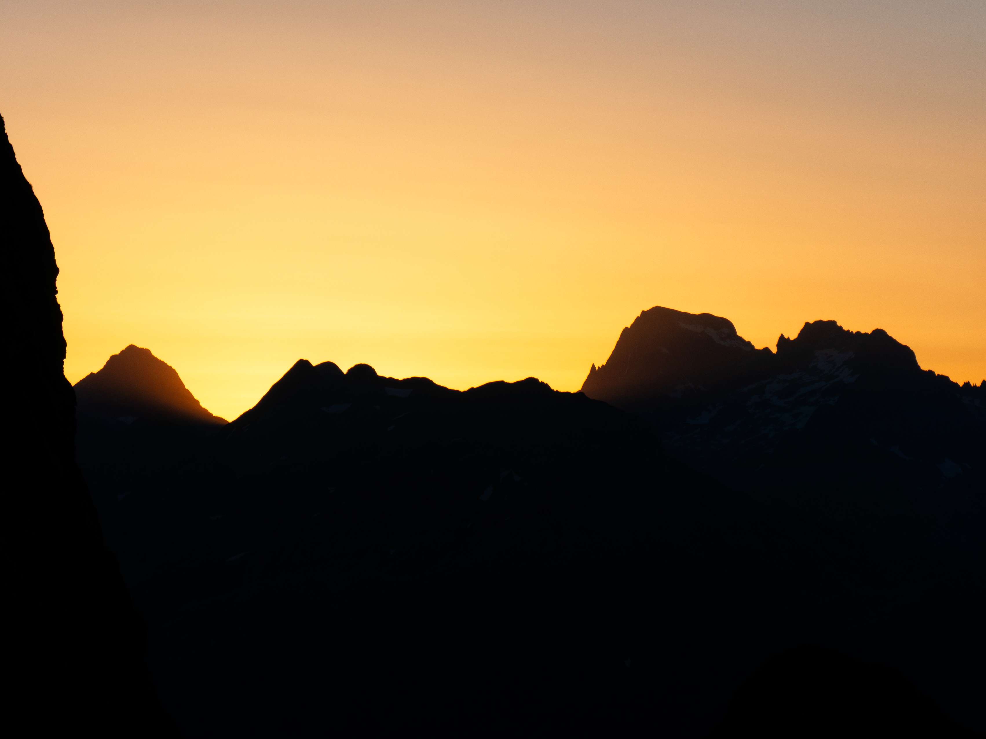 Mientras subimos hacia el collado, el sol empieza a hacer acto de presencia, tiñendo de dorado tanto el cielo como las cimas del Palas, el Balaitús y las Frondellas, mientras que los Picos de Soques permanecen en una penetrante oscuridad. En el Balaitús y las Frondellas se distinguen a la perfección las afiladas e inconfundibles siluetas de la Aguja Lamathe y la Aguja Cadier, adosadas a sus respectivas cumbres principales.