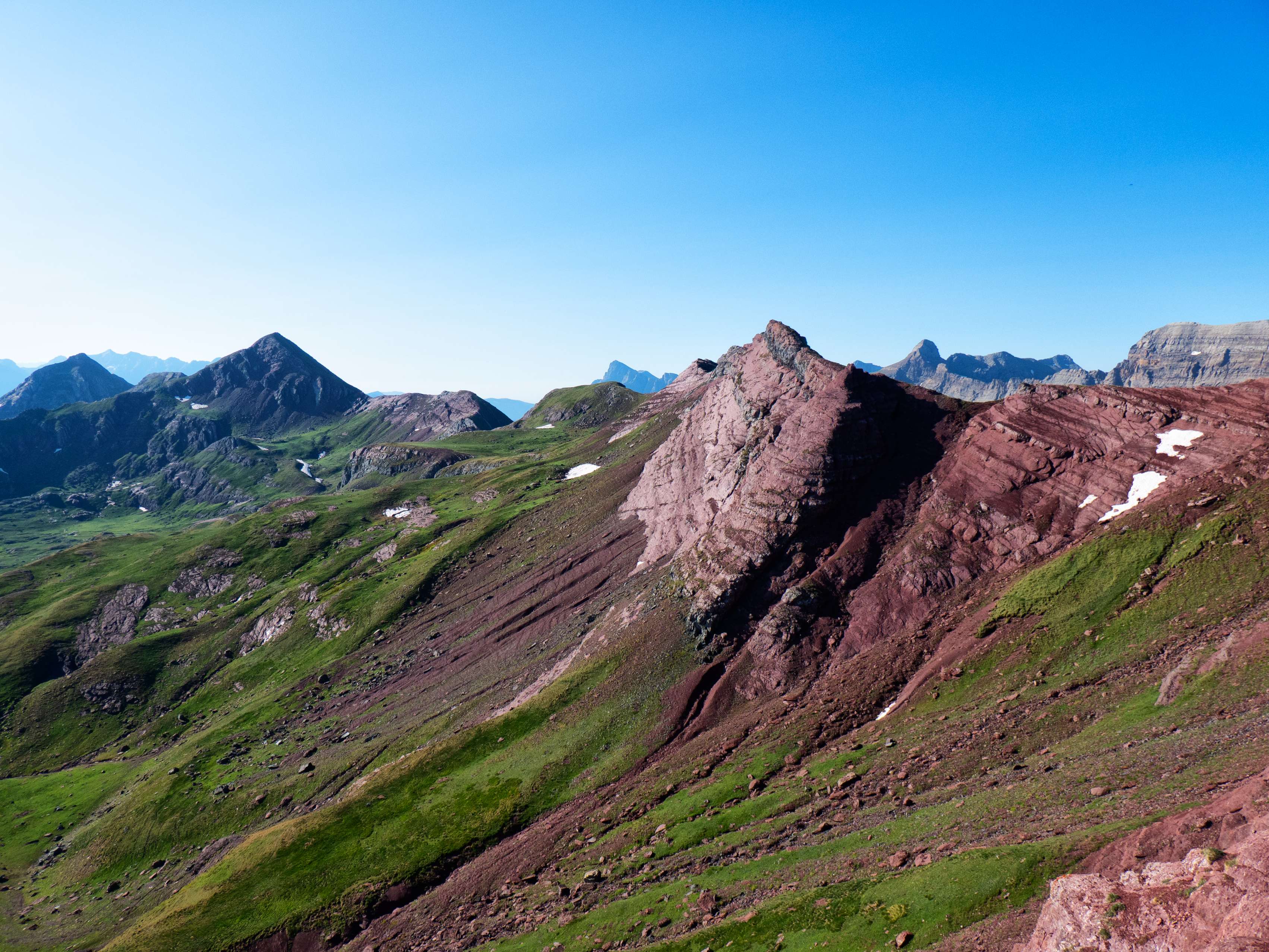Subimos por el mismo filo de la arista, lo que nos permite contemplar la cresta que cierra los Llanos de Anayet por el sur y que se prolonga de la montaña a la que estamos subiendo hasta el lejano Arroyeras. Esta cresta, cuya cota principal es el Garmo de Izás, tiene tramos bastante estéticos, como el descarnado muro rosáceo que se ve en la fotografía.