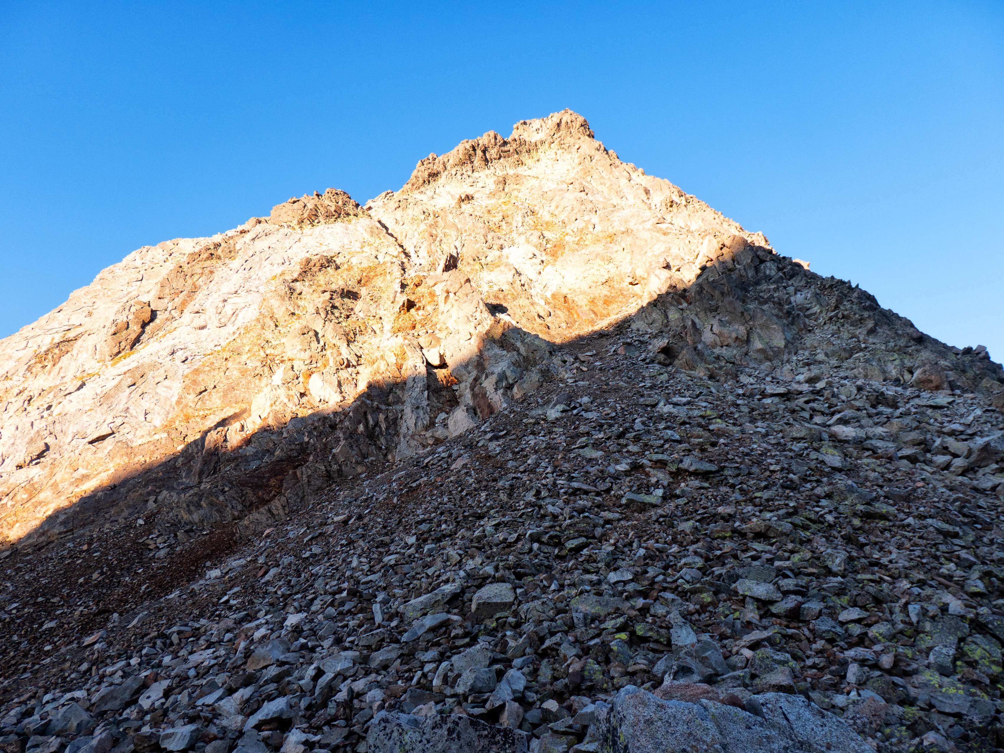 Pero nuestro objetivo está en el lado opuesto. Irguiéndose muchos metros sobre el Collado de Pondiellos, está la Aguja de Pondiellos (aunque desde aquí aún no distingamos su cima). Esta feroz pared, de apariencia infranqueable, tiene un punto débil: una canal que la corta en diagonal y que permite acceder de forma sencilla a su cresta. Abandonando el sendero, nos disponemos a remontar la movediza pedrera de su base para...