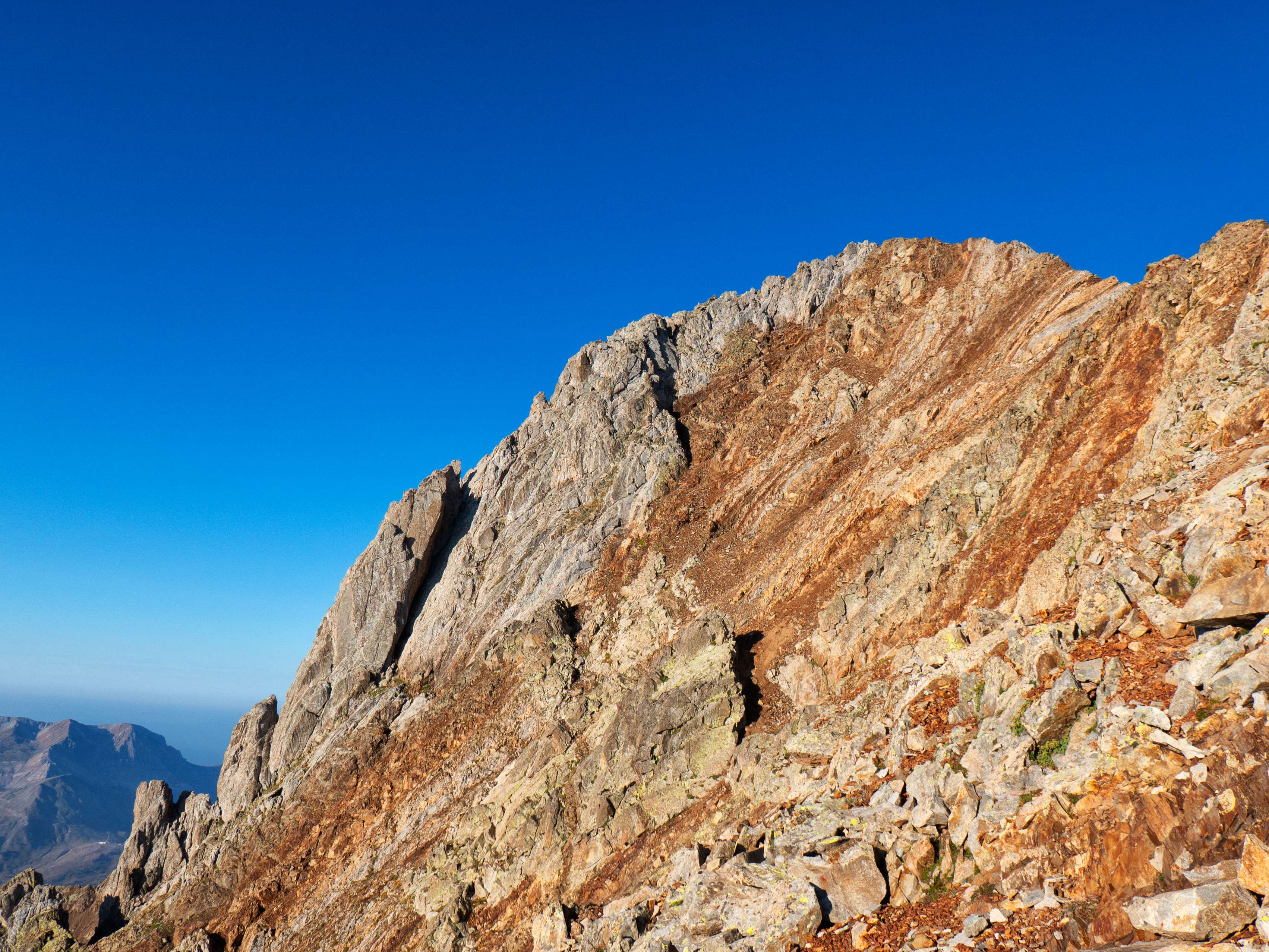 Sobre los 2.900 metros, la canal desemboca en la cresta cimera de la Aguja de Pondiellos, cuya agreste cumbre ya vemos en lo alto de una podrida ladera metamórfica. A partir de aquí y hasta el Garmo Negro, la calidad de la roca se torna deleznable, lo que aporta la dificultad quizás más marcada de la ruta. Aunque los pasos de trepada nunca sean complicados para el montañero acostumbrado a este tipo de terreno, que toda la roca que toques con las manos y los pies se desmenuce ante el más mínimo contacto no da mucha seguridad.