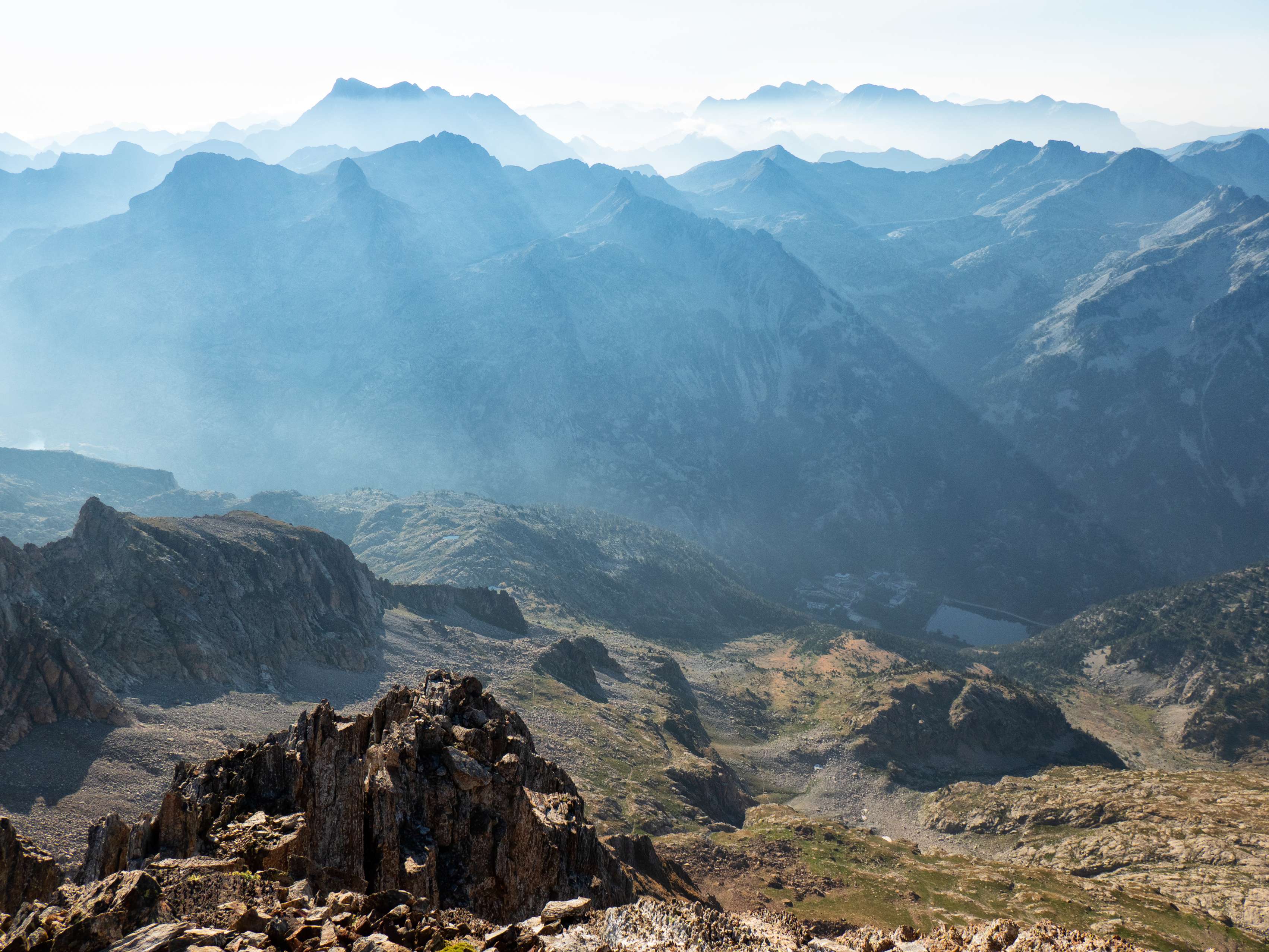 Asomándonos con cuidado a los abismos meridionales de la cima, divisamos prácticamente todo el trayecto realizado desde los Baños de Panticosa, aún sumidos en la oscuridad debido a la profundidad del agujero en el que se encuentran, hasta el Collado de Pondiellos, pasando por la Mallata Alta, donde hemos pasado la noche. Más allá de las montañas orientales del valle del Caldarés asoman entre la calima el cuarto y el tercer macizo más altos del Pirineo: el Vignemale y el de Ordesa, con las Tres Sorores algo deslucidas por la presencia, más imponente desde nuestra ubicación, de la gran pared del Taillón.