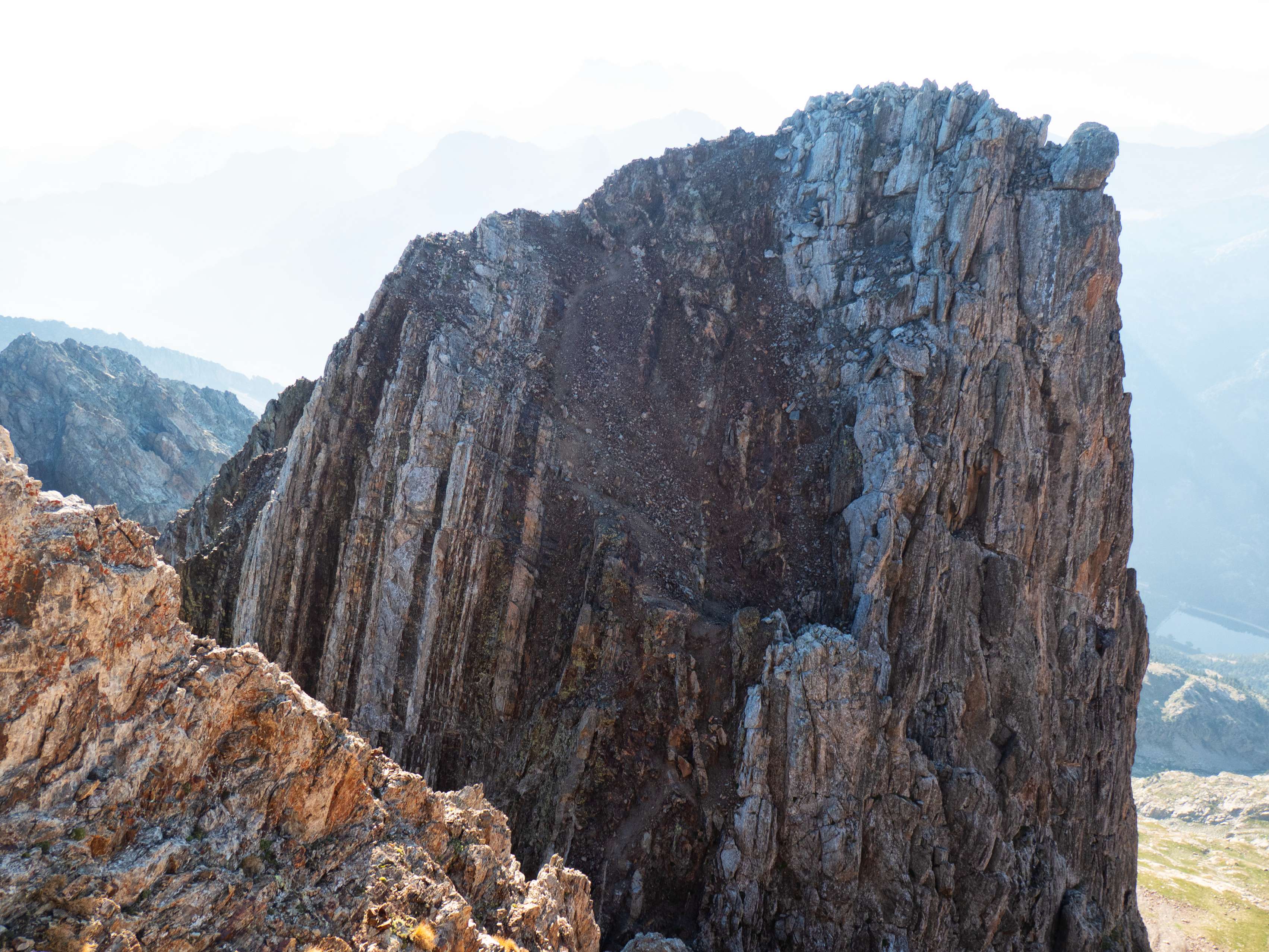 Poco a poco, el adusto perfil de la Aguja de Pondiellos va quedando a nuestra altura, descubriéndose su cara meridional, absolutamente vertical. Si nos fijamos bien, se aprecia el senderillo que baja de su cima hasta la brecha. Como se ve, el terreno no permite dar un traspiés.
