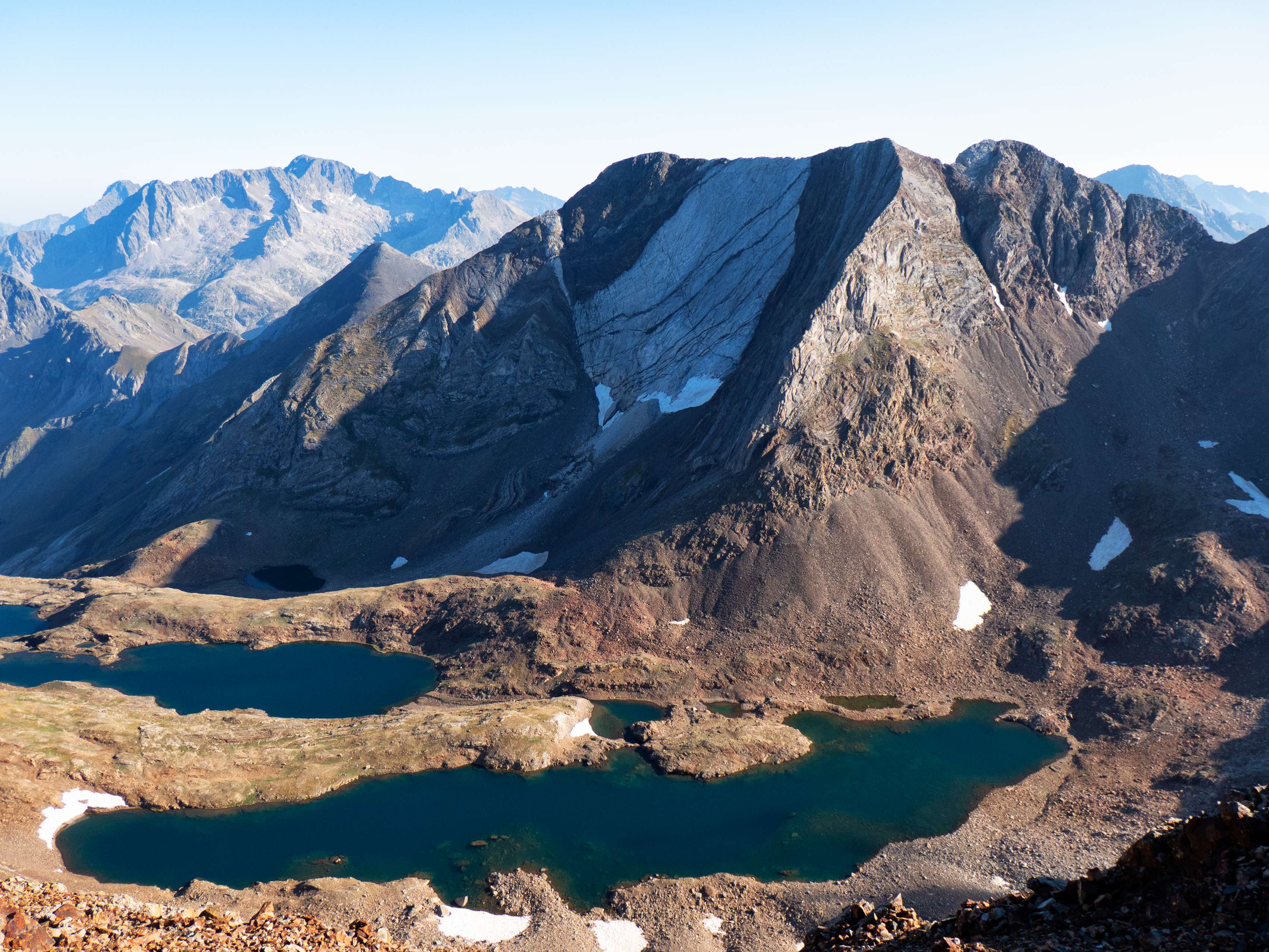 Sin duda alguna, la estampa más bonita que se puede obtener desde esta cima es contemplar los <a href="https://triptomontes.com/circular-a-los-picos-del-infierno-desde-los-banos-de-panticosa-por-los-ibones-azules-y-retorno-por-pondiellos/">Picos del Infierno</a>, una de las montañas más singulares de todo el Pirineo, alzando su descarnada mole multicolor, con la gran placa de mármol separando el Infierno Occidental del Central, por encima de los alargados ibones de Pondiellos. ¡Qué imagen!