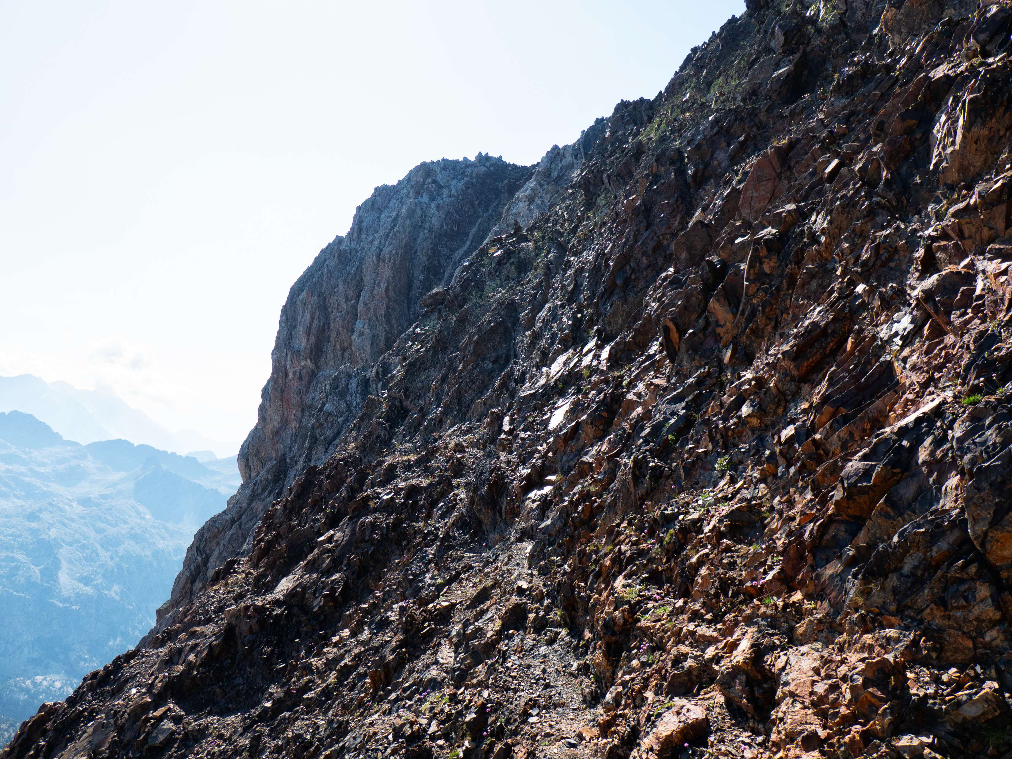 Cuando alcanzamos la base de la pared, la recorremos por debajo siguiendo un inestable trazo de sendero y algún hito que confirma que la ruta que seguimos es la correcta.